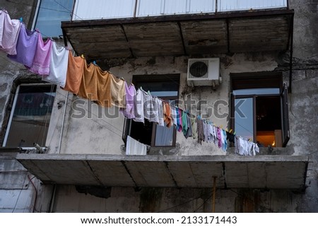 old gray concrete panel house with windows where the cords are placed on which the clothes are hanging and drying
