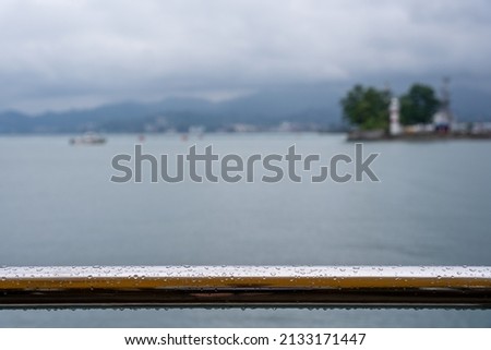 a wet shiny metal railing with a blurred seascape in the background