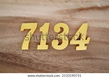 Wooden  numerals 7134 painted in gold on a dark brown and white patterned plank background.