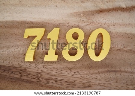 Wooden  numerals 7180 painted in gold on a dark brown and white patterned plank background.