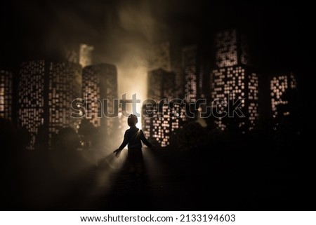 Cartoon style city buildings. Realistic city building miniatures with lights. background. Silhouette of a man looking on night city. Selective focus