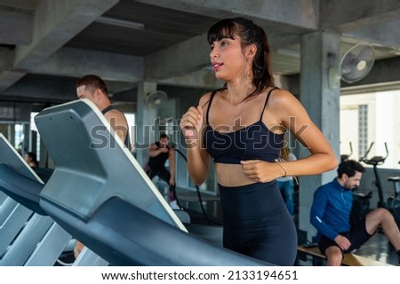 Healthy athletic woman in sportswear jogging workout exercise on treadmill at fitness gym. Wellness female do sport training cardio on running machine at sport club. Health care motivation concept Royalty-Free Stock Photo #2133194651