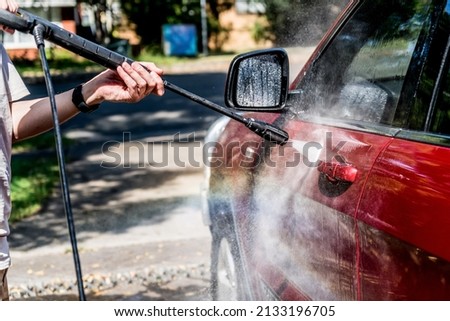 Selective focus shot of washing a red Suv 4wd car with high pressure washer cleaner. Car wash. Rainbow water drops Royalty-Free Stock Photo #2133196705