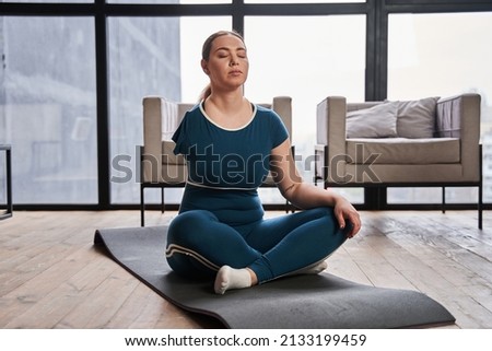 Caucasian woman with amputee arm meditating at home in the morning and practicing yoga Royalty-Free Stock Photo #2133199459