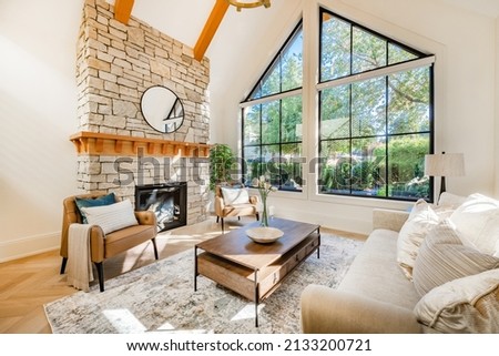 Open concept living room with fireplace wooden beams black door frames and autumn colors
