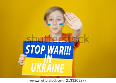 the boy stretched out a poster in front of him with the inscription stop the war in Ukraine and shows a stop sign with his palm