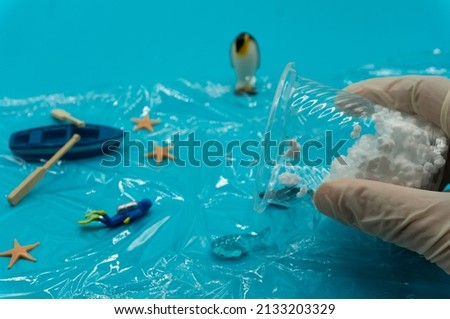 ecological issues, ecological conservation, marine litter, plastic pellets in sea,marine pollution，marine damage.White gloved hands,pour particles of plastic waste into shrinking sea. sustainable,