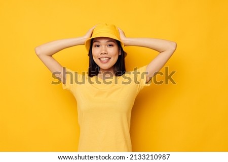 Charming young Asian woman wearing a yellow hat posing emotions yellow background unaltered