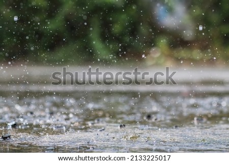 Rain is falling heavily due to sudden thunderstorms and summer storms, causing the downpours to not be able to drain quickly into the sewers, causing rain water to pool on the road surface. Royalty-Free Stock Photo #2133225017