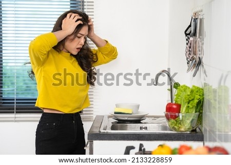 tired woman washing dishes in the sink in the kitchen at home