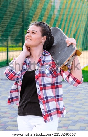 Cute millennial woman smile happy walking down the street with her skateboard. sun backlight and freedom rebel independent concept. Spending day for active board hobby