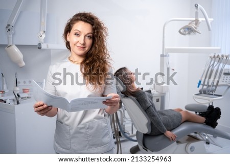 Portrait of a female dentist in a clinic. dental clinic and oral health concept. a doctor with a client's card looks at the camera. copy space.