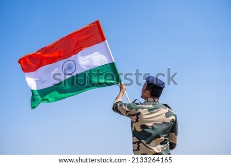 Indian army soldier holding waving Indian flag on top of mountain - concept of independence or repubilc day celebration, patriotisms and freedom Royalty-Free Stock Photo #2133264165
