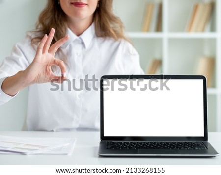 Ok gesture. Official woman. Online education. Pretty unrecognizable smiling lady showing approving sign opened laptop blank screen in light room interior defocused.