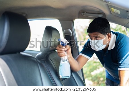 cab or car taxi driver with medical face mask sanitizing passenger seat - concept of coronavirus covi-19 safety measures, hygiene and medical protuction Royalty-Free Stock Photo #2133269635