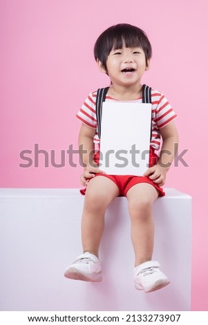 Cute Little boy holding holding an blank card on pink background.