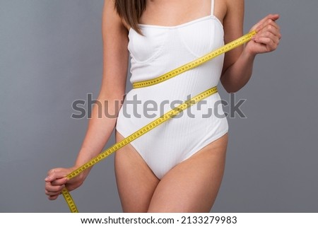 Young girl measuring her waist. Woman slim body.
