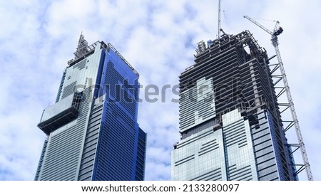 Skyscraper building under construction with tower crane and blue sky background  Royalty-Free Stock Photo #2133280097