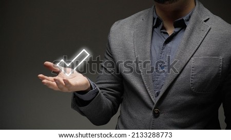 A close-up shot of a businessman holding a 3D rendered check mark icon interface in his hand