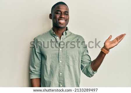 Young african american man wearing casual clothes smiling cheerful presenting and pointing with palm of hand looking at the camera. 