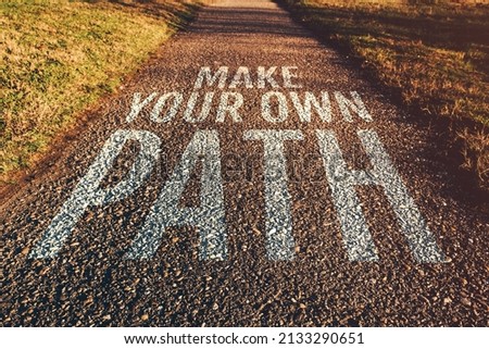 Make your own path motivational quote on footpath leading through park in diminishing perspective, selective focus