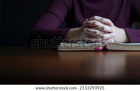 Woman hands in prayer posture on top of open bible. Copy space.