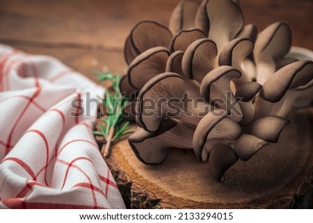 closeup picture of oyster mushrooms on top of antique wooden chopping board and kitchen towel promoting healthy living 