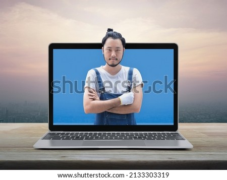 Asian mechanic car engine in uniform with tools and modern laptop computer on wooden table over office city tower and skyscraper at sunset, vintage style, Business repair car service online concept Royalty-Free Stock Photo #2133303319