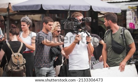 Behind the scenes. Film crew team shooting movie scene on outdoor location. Group filmmaking set production
