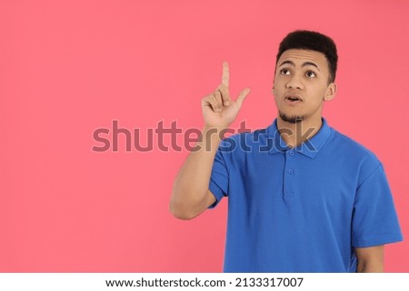 Young man in blue polo on pink background