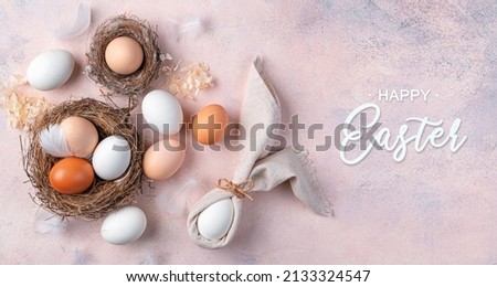 Easter background with eggs in a nest and an Easter bunny from a napkin on a soft pink background. The concept of a happy Easter. Top view.