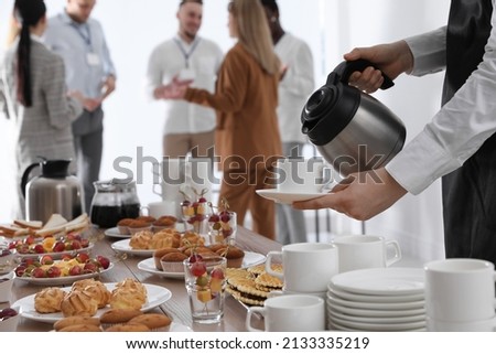 Waitress pouring hot drink during coffee break, closeup Royalty-Free Stock Photo #2133335219