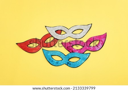 Holidays image of carnival party sequins masks over yellow background. view from above