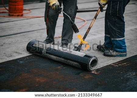 Construction workers installing bituminous membrane waterproofing system insulation using blowtorch and gas Royalty-Free Stock Photo #2133349667