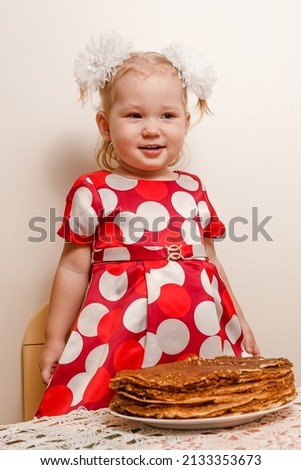 a two-year-old girl and a large plate of pancakes. Maslenitsa holiday. pancakes and children