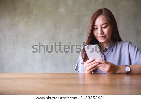 Portrait image of a beautiful young asian woman holding and using mobile phone