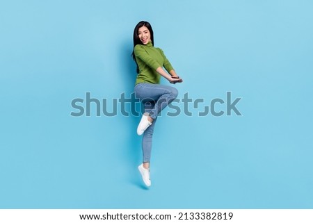 Full size photo of impressed young brunette lady jump yell wear jumper jeans shoes isolated on blue background.