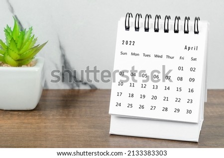 The April 2022 desk calendar with plant pot on wooden table.