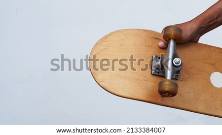 Right hand carrying skateboard. White background.                              