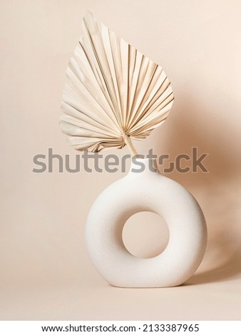 Round stylish ceramic vase with dried palm leaf casting shadows on the wall. Beige background. Front view. Copy space Royalty-Free Stock Photo #2133387965
