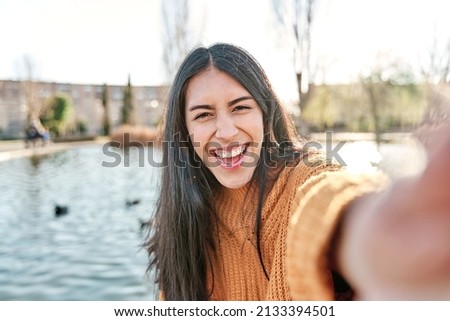 Portrait of charming young woman smiling while taking selfie photo.