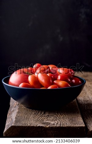 Small Red Tomatoes in Bowl on Old Wooden Background Vegetable Vertical Dark Photo