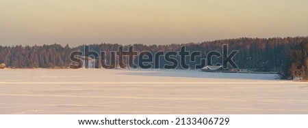 Photography of winter soft cold day, Russian countryside. Frozen river covered by snow. Camp site. Coming pink sunny sunset. Beautiful view.  Concept of the beauty in nature. Panoramic image