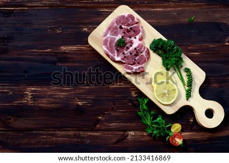 tasty fresh meat with cream on wooden plate served with lemon, variety of seasonings, and vegetables ready to be eaten by using fork and steak knife
