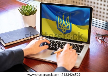 Support Ukraine, donate help Ukrainian people. flag on computer laptop screen. Business office desk background