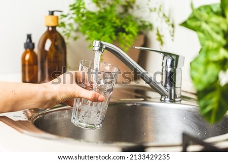 Female hand filing a glass with clean tap water  Royalty-Free Stock Photo #2133429235