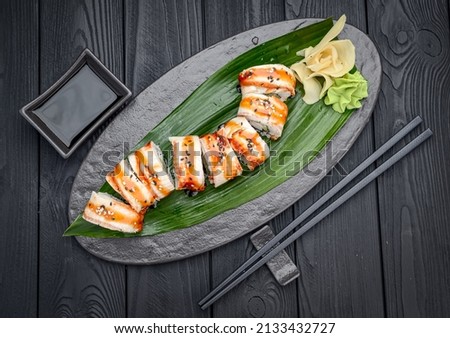 Sushi roll dragon with smoked eel and shrimp. Traditional delicious fresh sushi roll set on a black background. Sushi menu. Japanese kitchen, restaurant. Asian food