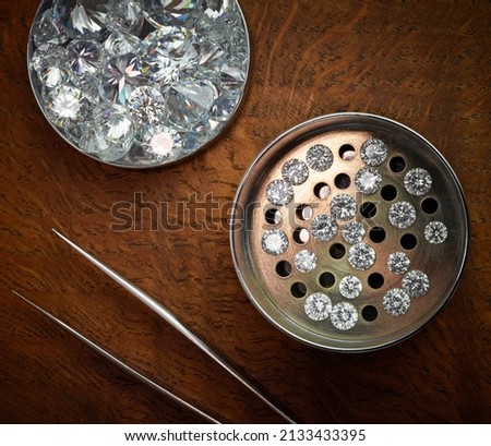 Loose Polished Round Diamonds in Sieve on Dark Wood Background Royalty-Free Stock Photo #2133433395