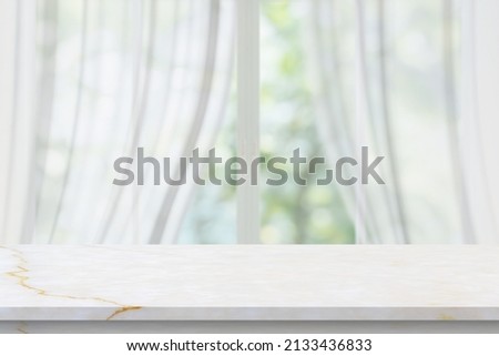Marble table top on blur room interior with window curtain background