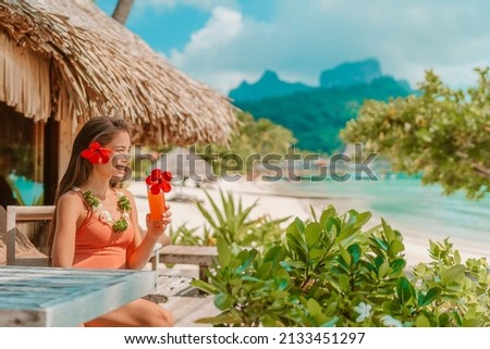 Breakfast at luxury hotel room on beach. Asian woman drinking fruit juice morning on summer vacation travel in Bora Bora island, Tahiti French Polynesia landscape. Happy tourist relaxing on holiday. Royalty-Free Stock Photo #2133451297